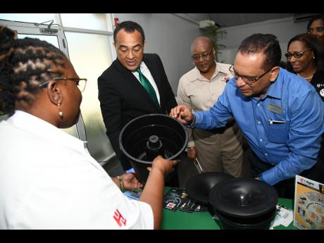 Rudolph Brown/Photographer Dr. Christopher Tufton, (second left), minister of health looks at the In 2 Care mosquito-control system with (from left) Odean Bradshaw, marketing and business development manager of Hardware and Lumber Agro; Audrey Hinchcliffe, CEO and chairman, Manpower and Maintenance Services (MMS) Ltd and Caribbean Health Management Ltd; Raoul Persuad, account executive, Univar Environmental Sciences; and Olive Downer Walsh, deputy CEO of Hardware and Lumber Ltd. They were at a client seminar on mosquito-borne diseases hosted by MMS Ltd in collaboration with Caribbean Health Management Ltd and H&L Agro at Spanish Court Hotel in New Kingston yesterday. The In 2 Care is a double killing agent (larvacide and fungicide) that attracts Aedes aegypti mosquitoes, contaminates and uses them to infect breeding sites so they can no longer transmit diseases.